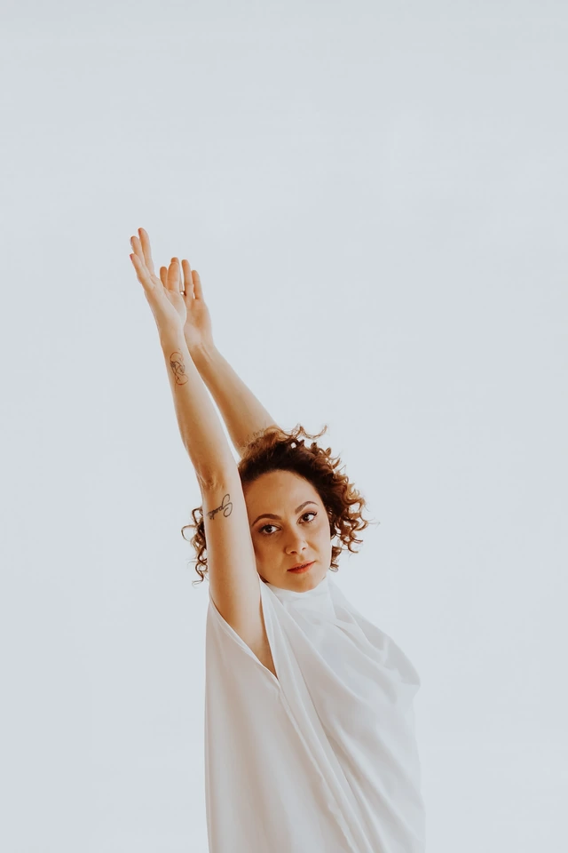 Ingrid em um gesto de dança, com os dois braços elevados