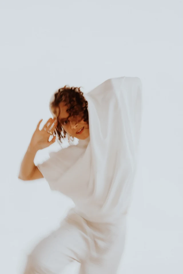 Ingrid em um gesto de dança com um tecido branco
