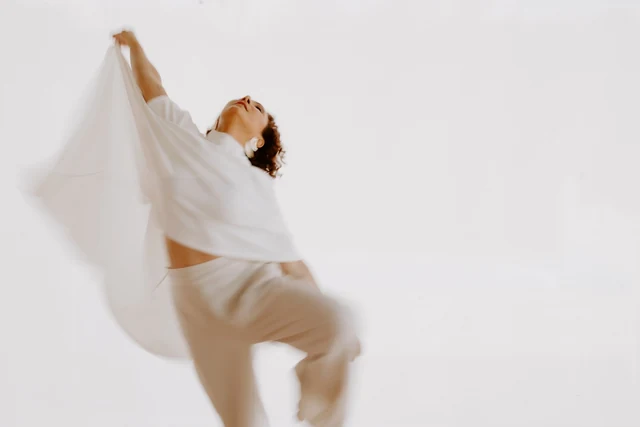 Ingrid em um movimento amplo de dança com tecido claro
