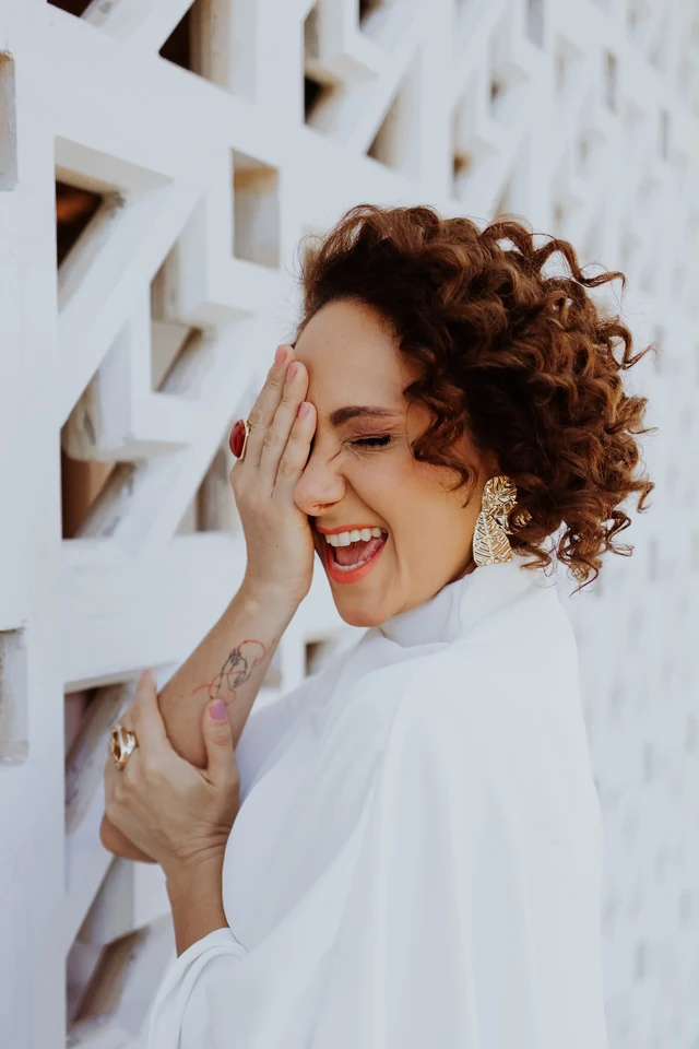 Ingrid sorrindo junto a uma parede de elementos vazados